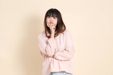 Pembe ultraviyole koruyucu kapüşonlu ceket giyen genç Asyalı kadın bej arka plan, güneş koruma giysisi konseptine karşı düşünüyor..