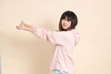 Pembe ultraviyole koruyucu kapüşonlu ceket giyen genç Asyalı kadın bej bir arka plan, güneş koruması giysi konseptine karşı yorgun düşmüş..