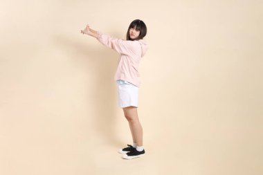 Pembe ultraviyole koruyucu kapüşonlu ceket giyen genç Asyalı kadın bej bir arka plan, güneş koruması giysi konseptine karşı yorgun düşmüş..