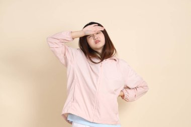 Pembe ultraviyole koruyucu kapüşonlu ceket giyen genç Asyalı kadın bej arka plan hastalıklı, güneş korumalı giysi konseptine karşı.