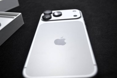 Üçlü kameralı gümüş iPhone 'un arka planı ve siyah yüzey sergilenen parlak tasarım, premium bitiş ve ekommerce ve teknoloji ürünü görselleri için modern markalaşma üzerine Apple logosu.