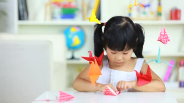 Chica encantadora jugando grúas de papel interior — Vídeo de stock