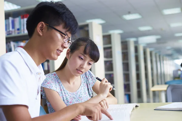 Jóvenes estudiantes universitarios estudian juntos en la biblioteca —  Fotos de Stock