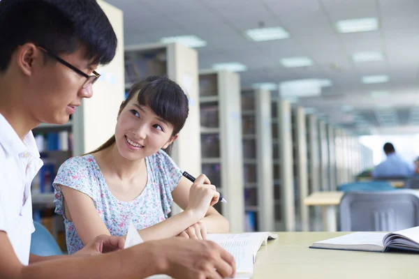 Jóvenes estudiantes universitarios estudian juntos en la biblioteca —  Fotos de Stock