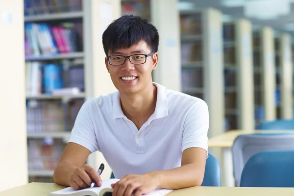 Jovem estudante universitário olhando para câmera sorriso na bibliotecária — Fotografia de Stock