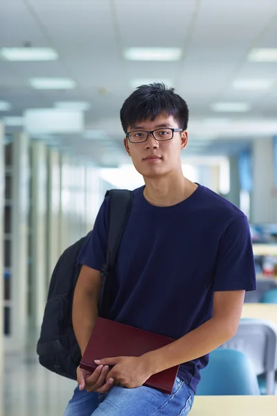 Junger männlicher College-Student blickt in die Bibliothek und lächelt in die Kamera — Stockfoto