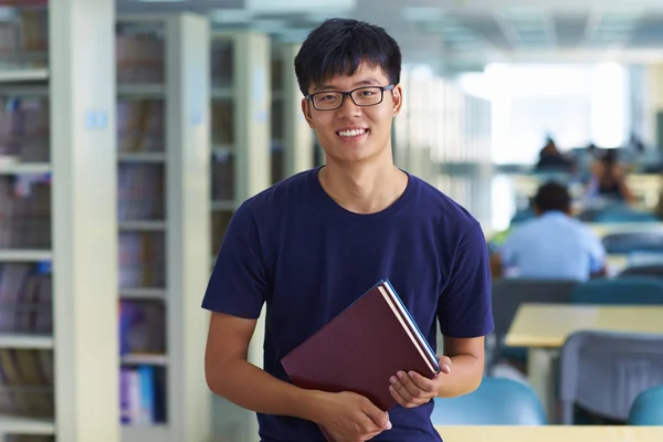 Junger männlicher College-Student blickt in die Bibliothek und lächelt in die Kamera — Stockfoto