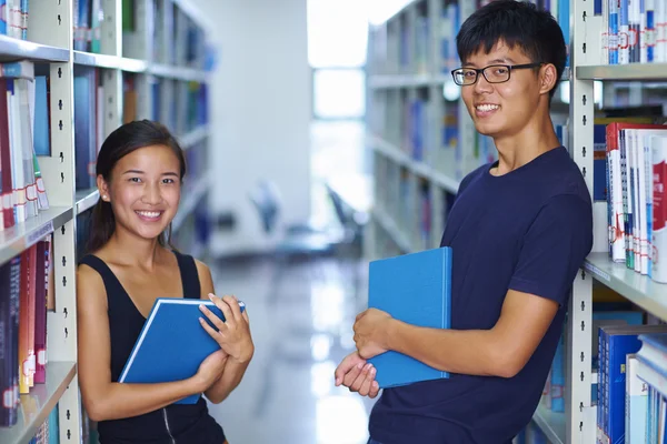 Два молодых студента азиатского колледжа улыбаются перед камерой в библиотеке — стоковое фото