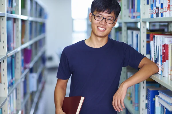 Joven estudiante universitario mirando la sonrisa de la cámara en la biblioteca —  Fotos de Stock