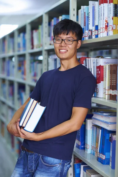 Joven estudiante universitario mirando la sonrisa de la cámara en la biblioteca —  Fotos de Stock