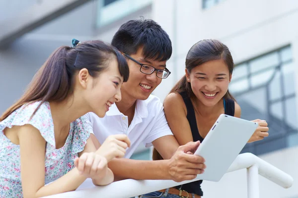 Jovens felizes usando tablet ao ar livre — Fotografia de Stock