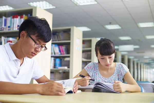 Jóvenes estudiantes universitarios estudian juntos en la biblioteca —  Fotos de Stock