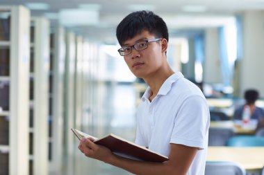 Genç erkek üniversite öğrencisi librar kamera gülümseme bakarak