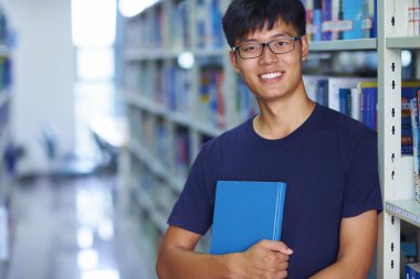 Genç erkek üniversite öğrencisi librar kamera gülümseme bakarak