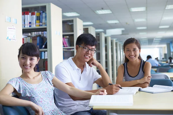 Jóvenes estudiantes universitarios estudian juntos en la biblioteca —  Fotos de Stock