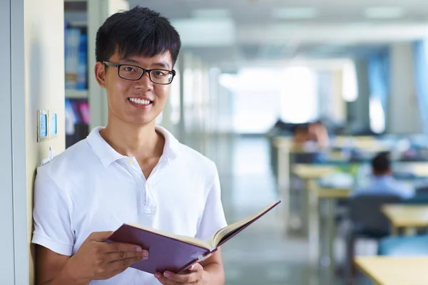 Joven estudiante universitario mirando la sonrisa de la cámara en la biblioteca —  Fotos de Stock