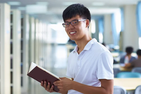 Junger männlicher College-Student blickt in die Bibliothek und lächelt in die Kamera — Stockfoto