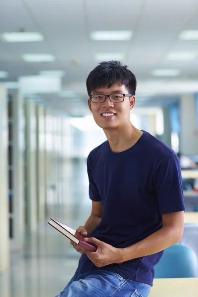 Jovem estudante universitário olhando para câmera sorriso na bibliotecária — Fotografia de Stock