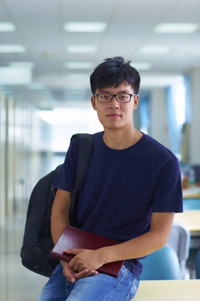 Junger männlicher College-Student blickt in die Bibliothek und lächelt in die Kamera — Stockfoto