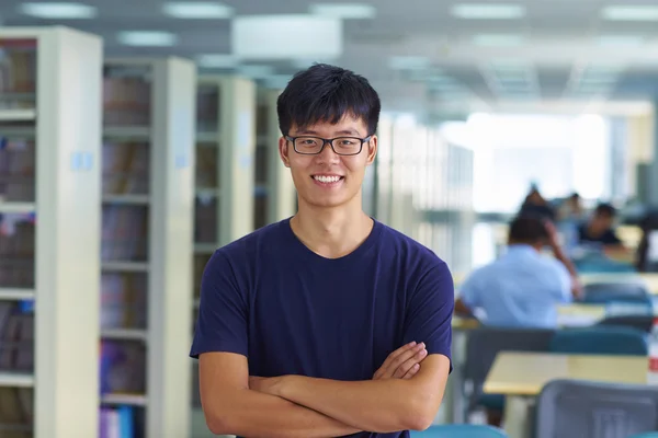 Jovem estudante universitário olhando para câmera sorriso na bibliotecária — Fotografia de Stock