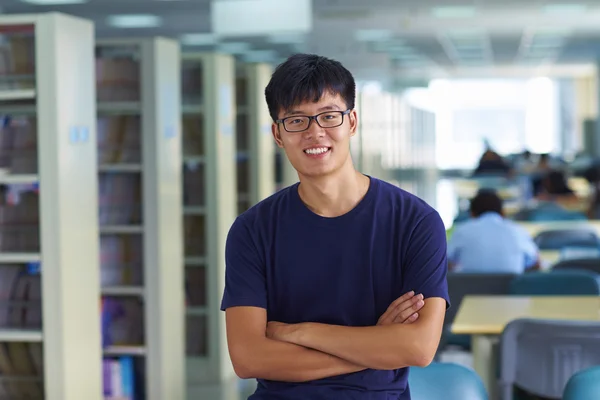 Jovem estudante universitário olhando para câmera sorriso na bibliotecária — Fotografia de Stock