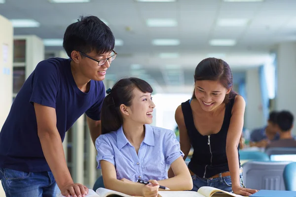 Jóvenes estudiantes universitarios estudian juntos en la biblioteca — Foto de Stock