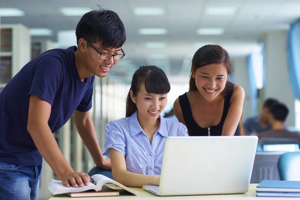 Jóvenes estudiantes universitarios estudian juntos en la biblioteca — Foto de Stock