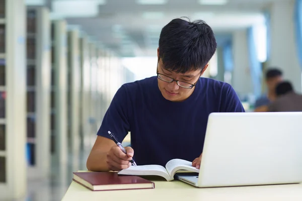 Один молодой человек учится в библиотеке — стоковое фото