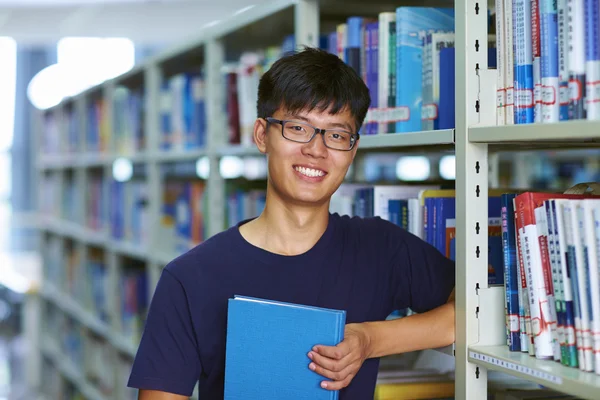 Jeune étudiant masculin regardant la caméra sourire dans la bibliothèque — Photo