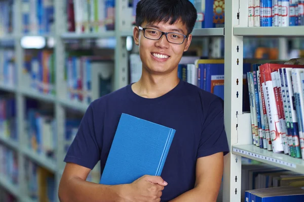 Joven estudiante universitario mirando la sonrisa de la cámara en la biblioteca —  Fotos de Stock