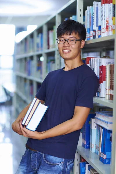 Genç erkek üniversite öğrencisi librar kamera gülümseme bakarak