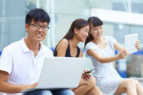 Genç Asyalı üniversite öğrencisi dizüstü veya tablet birlikte outd kullanarak — Stok fotoğraf