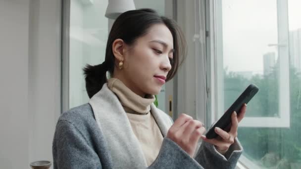 Ganska asiatisk kvinna tittar på mobiltelefon leende — Stockvideo