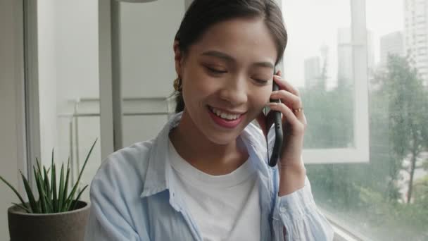Крупный план молодой азиатской женщины, разговаривающей по мобильному телефону — стоковое видео