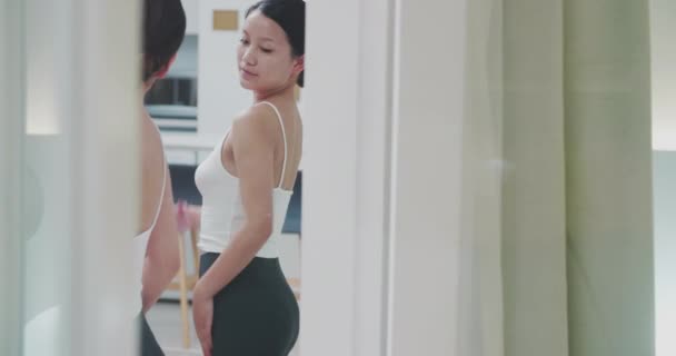 Schöne junge asiatische Frau schaut sich selbst im Spiegel an — Stockvideo