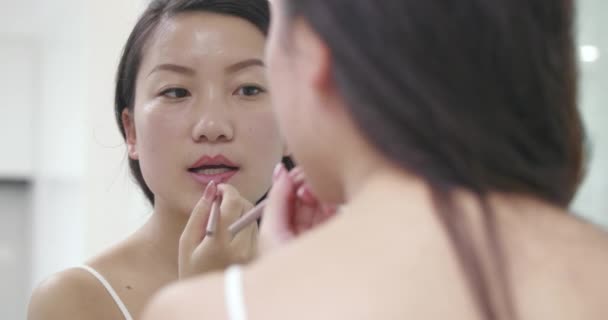 Nahaufnahme junge asiatische Frau, die Lippenstift aufträgt — Stockvideo