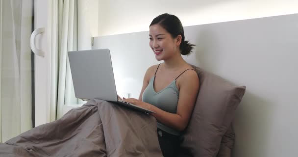 หญิงสาวเอเชียมีความสุขใช้แล็ปท็อปบนเตียง — วีดีโอสต็อก