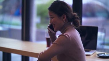 Mutlu iş kadını ofiste telefonda konuşuyor.