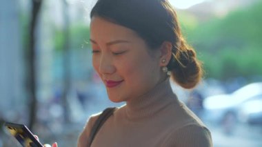 Şehirdeki açık havada telefon kullanan güzel bir Asyalı kadın.