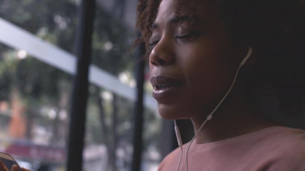Jonge Afrikaanse vrouw genieten van muziek met mobiele telefoon — Stockvideo