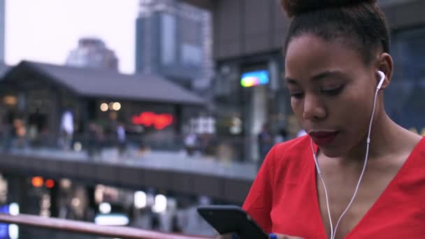 Genç Afrikalı kadın şehir caddesinde cep telefonuna bakıyor — Stok video