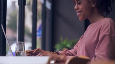 Kafede dizüstü bilgisayar kullanan sevimli Afrikalı kadın.