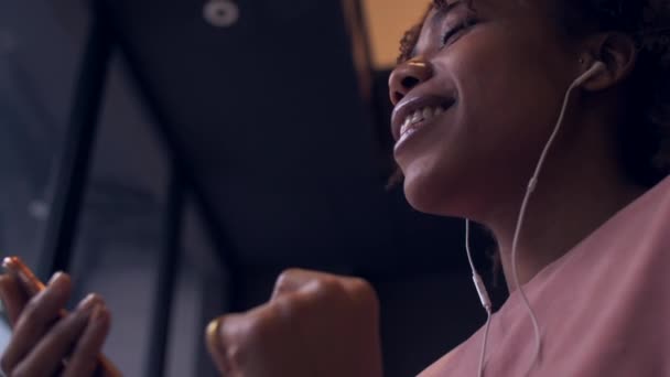 Mutlu Afrikalı genç zenci kadın telefonla müzik dinlemekten hoşlanıyor. — Stok video