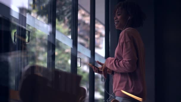 Jolie jeune fille africaine profiter de la musique sur téléphone mobile au ralenti — Video