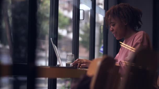 幸せな若いですアフリカの女の子使用してノートパソコンチャットオンラインでカフェ — ストック動画