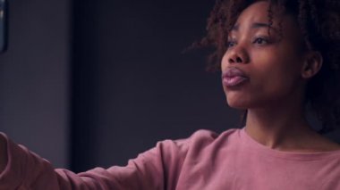 Mutlu genç Afrikalı kız cep telefonuyla selfie çekiyor.