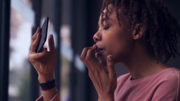 Junge Frau trägt Lippenstift vor Handy auf — Stockvideo