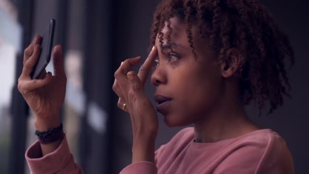 Jonge Afrikaanse vrouw make-up geconfronteerd met de mobiele telefoon — Stockvideo