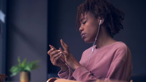 Wanita muda Afrika menggunakan ponsel menikmati musik menutup — Stok Video
