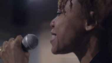 Sahnede şarkı söyleyen genç Afrikalı şarkıcıya yakın çekim